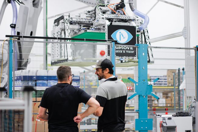 programmeur robot et concepteur mécanique devant la cellule de dépalettisation robotisée